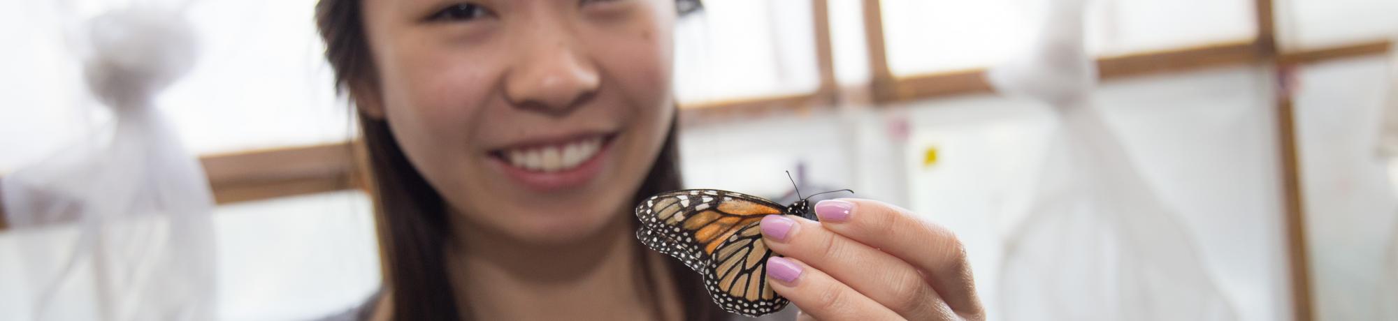 Student holding butterfly between fingers
