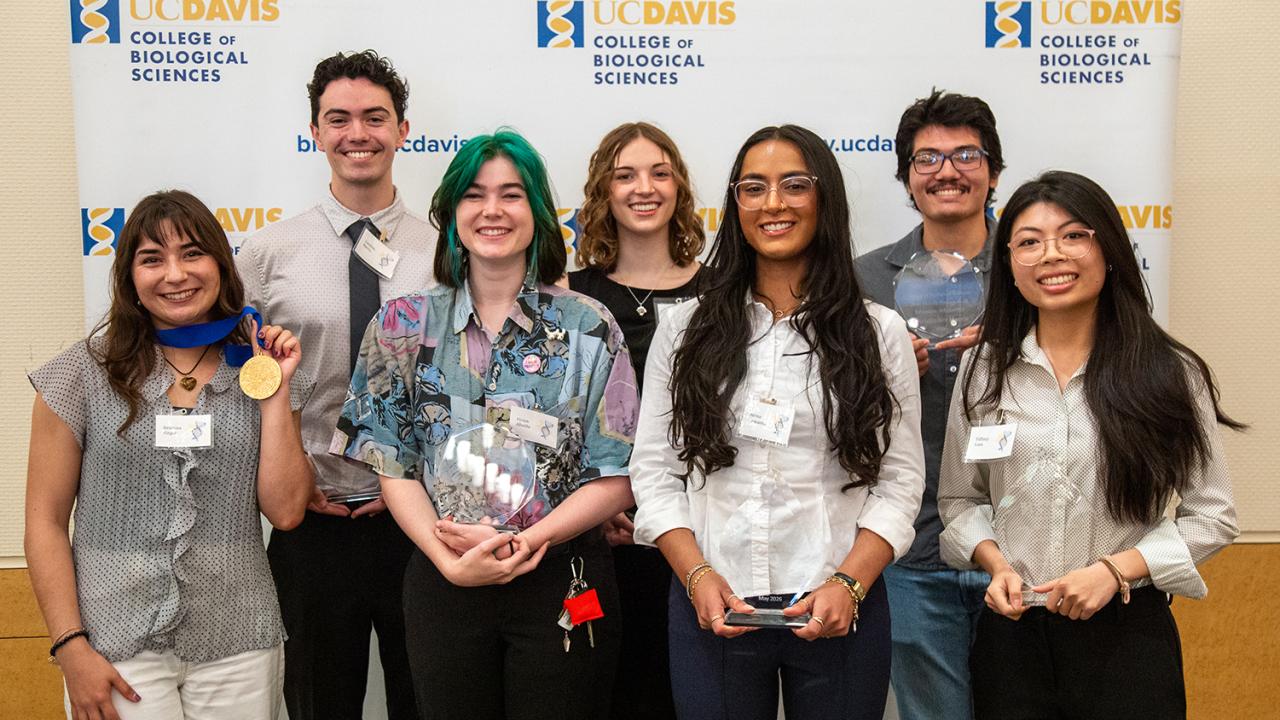 Seven smiling adults holding awards in front of UC Davis Health logo backdrop