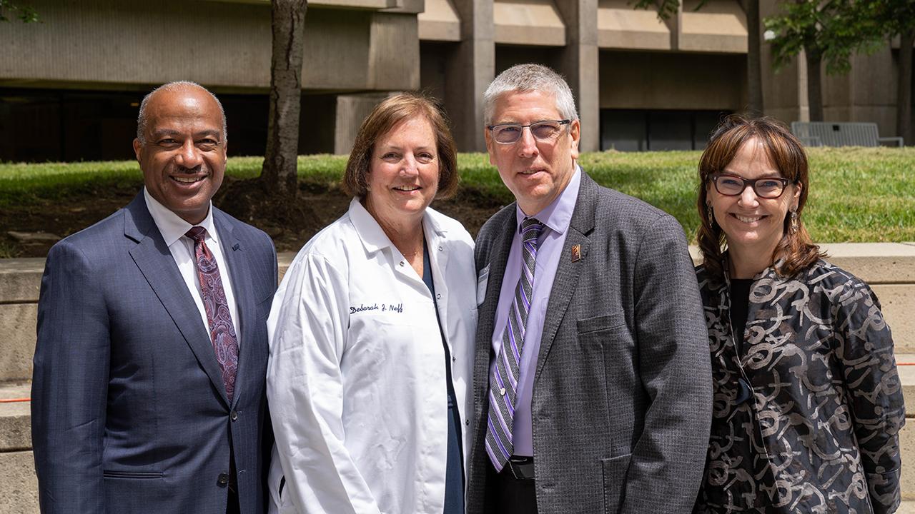 A group of leaders and the donor standing outside in sunlight with grass in the background.