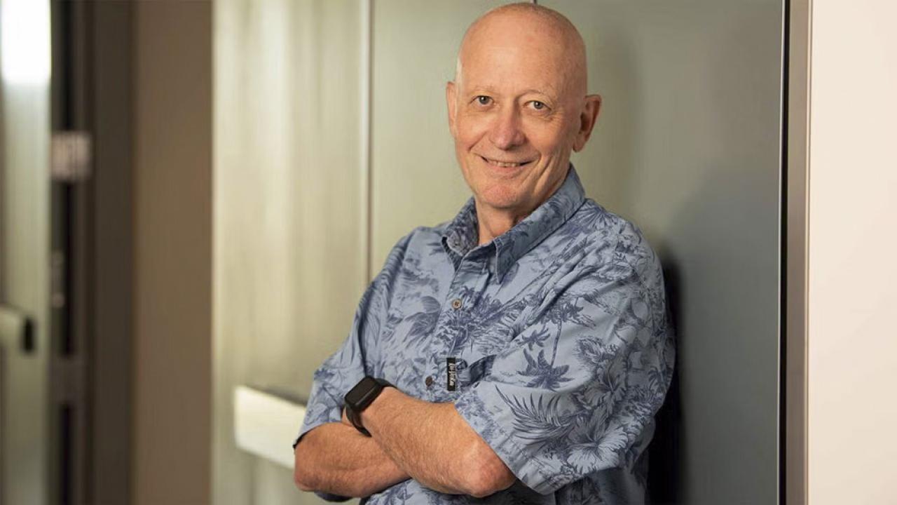 Portrait of a man in a blue shirt leaning against a wall