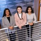 Three female students gathered in front of the DNA helix sculpture