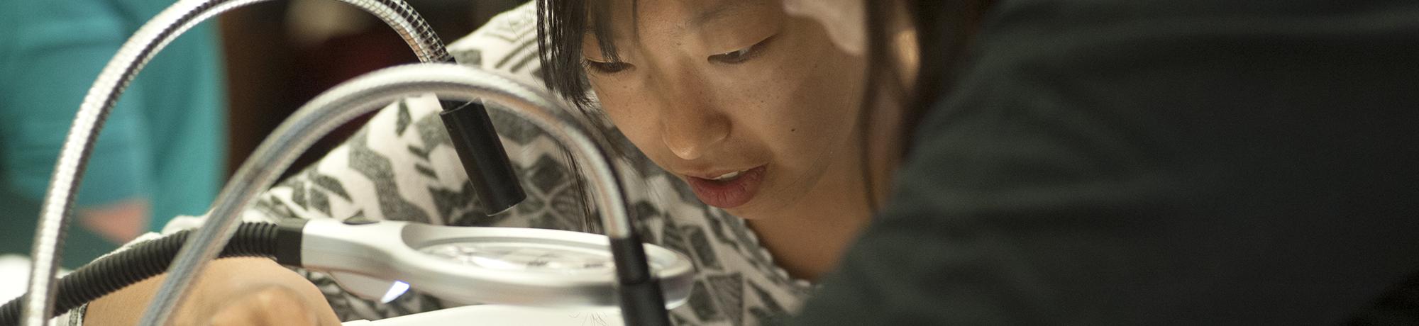 Female student examining object on table